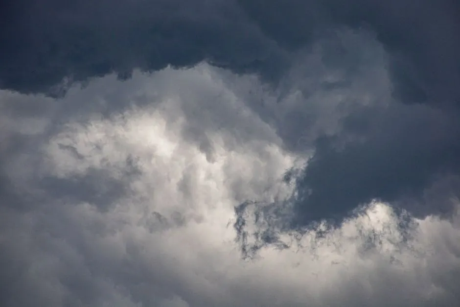 A dramatic view of dark clouds swirling in a moody, overcast sky.