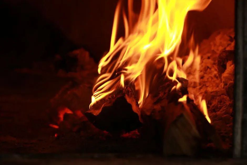 Close-up of firewood burning with bright flames in a wood-fired oven. Perfect for culinary and warmth themes.