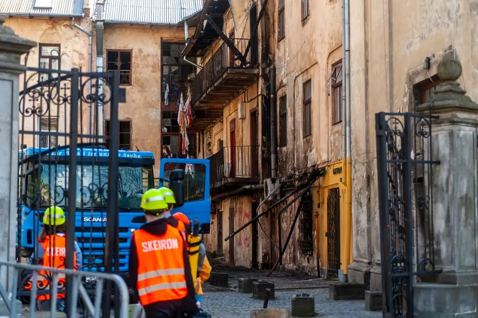Fire damage inspection of old building in Lviv, Ukraine, with emergency responders present.