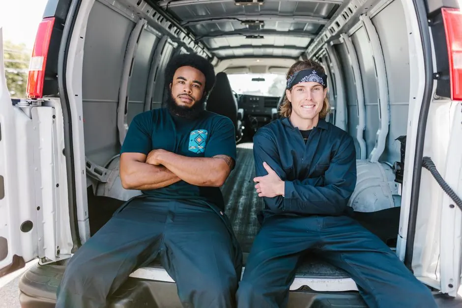 Two men sitting confidently inside an open van, showcasing teamwork and camaraderie.